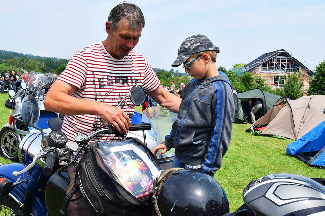 Ein Mann zeigt einem Jungen sein Motorad